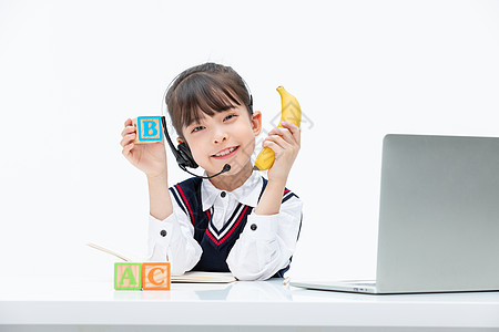 小女孩坐在电脑前手上拿着香蕉和字母图片