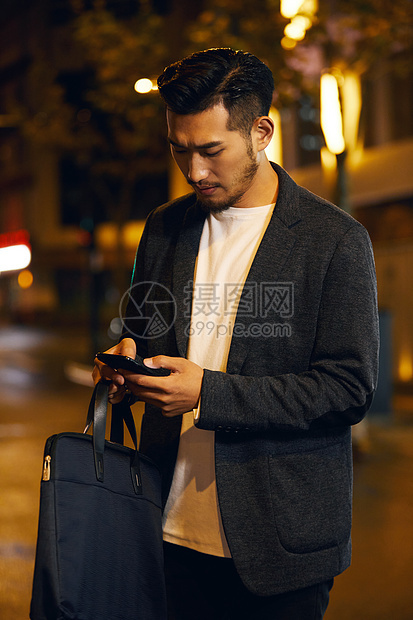 熬夜加班的商务男士低头玩手机图片