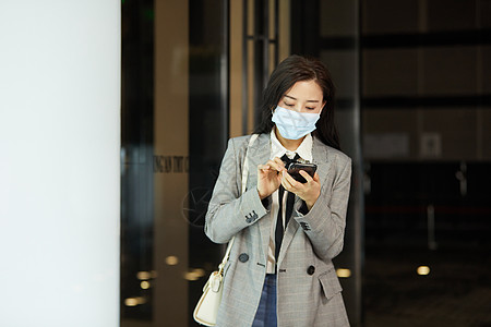 戴口罩女戴口罩的女白领下班低头玩手机背景