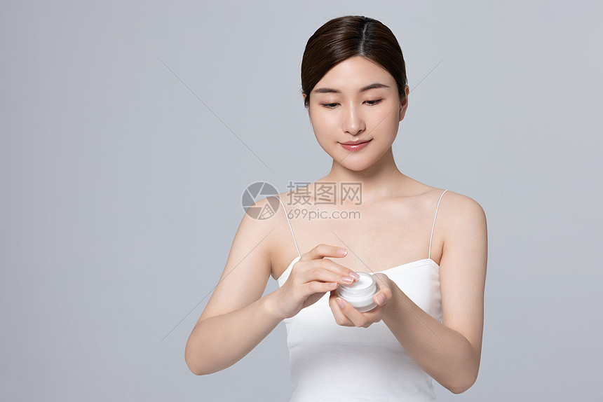 女性从容器里取出乳液图片