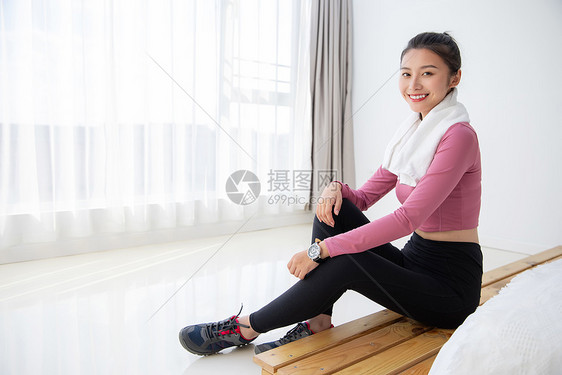 身材苗条的年轻美女居家运动坐在床边擦汗图片