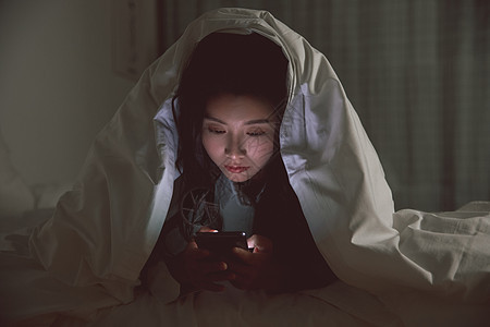 青年女性被窝里自熬夜玩手机游戏图片