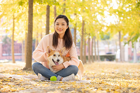 女性抱着宠物坐在地上图片