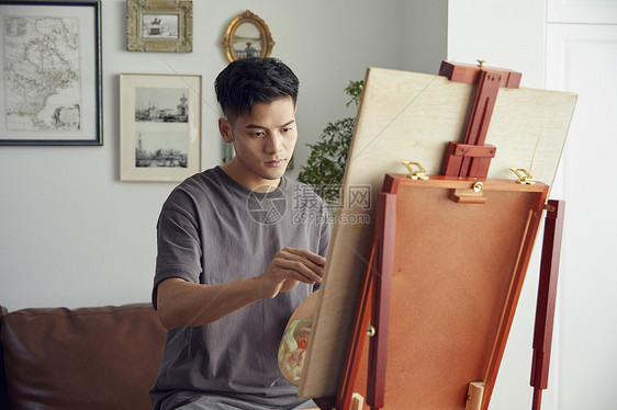 年轻男生在家创作油画图片