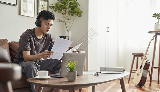 年轻男士居家戴耳机写歌图片素材