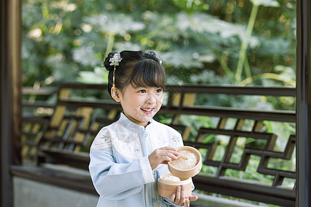 中国小女孩古装儿童小女孩拿蒸笼游玩公园背景