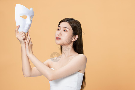 拿着面具伪装的美女女性面部保养图片素材