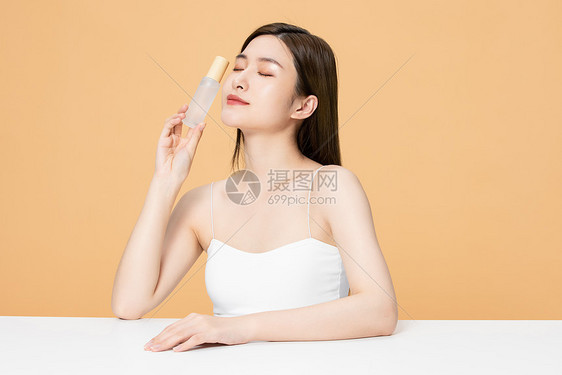 拿着保湿精华闭眼的美女图片