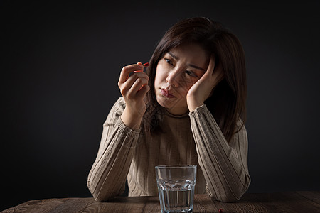 看着药物发呆的女性图片