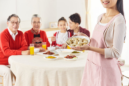 年轻妈妈春节给一家人端饺子背景图片