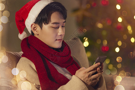 阳光男生圣诞节在家玩手机高清图片