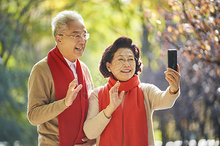 老人拿着手机新年装扮的老年夫妇视频通话打招呼背景