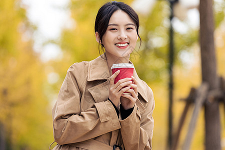 户外手捧咖啡的知性女青年背景图片