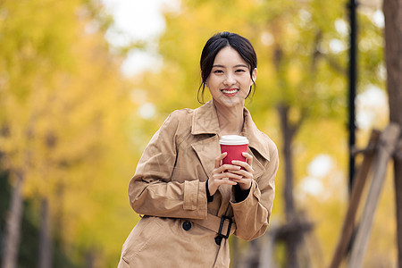 户外手捧咖啡的知性女青年图片