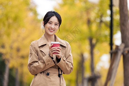 户外手捧咖啡的知性女青年图片