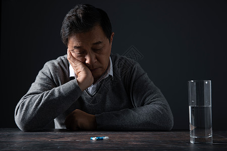 黑色孤独老人面对桌子上的药丸发呆背景