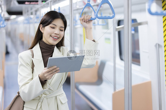 女生在地铁上开心地看着平板电脑图片