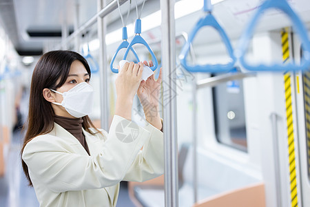 女性用消毒湿巾擦拭地铁的把手图片