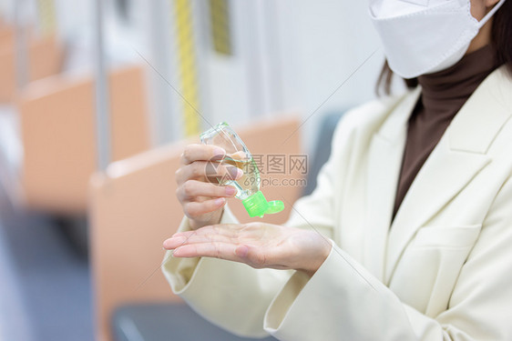 女性在地铁上使用免洗酒精消毒手部图片