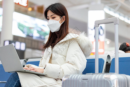 女性戴着口罩在高铁站使用笔记本电脑办公图片