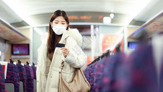 戴口罩的女性在火车车厢里寻找座位图片