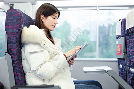 冬季保暖女性坐在火车上使用平板电脑背景