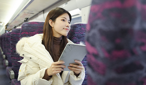 女生在火车上拿着平板电脑看窗外风景图片
