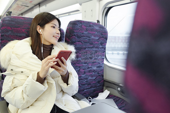 坐在火车上的女性戴着耳机听音乐图片
