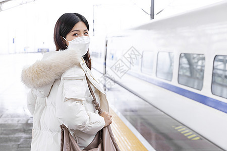 戴口罩的女性在列车站台等车图片