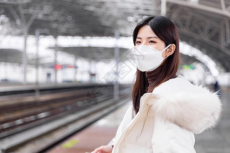 戴口罩的女性在列车站台等车图片