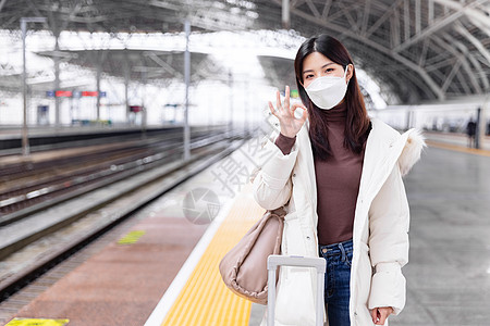 火车旅行戴口罩的女性在列车站台比ok手势背景