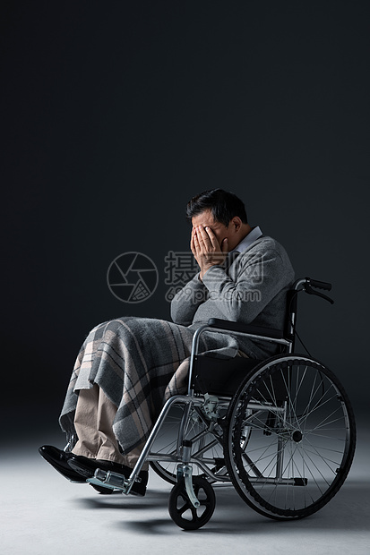 坐着轮椅的独居老人一个人在黑暗中捂着脸图片