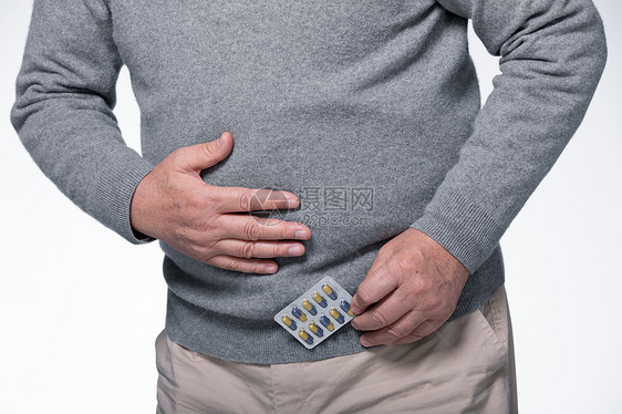 拿着药捂着肚子腹部疼痛的男性图片