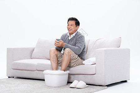 老年男性安逸的坐在沙发上使用泡脚盆图片