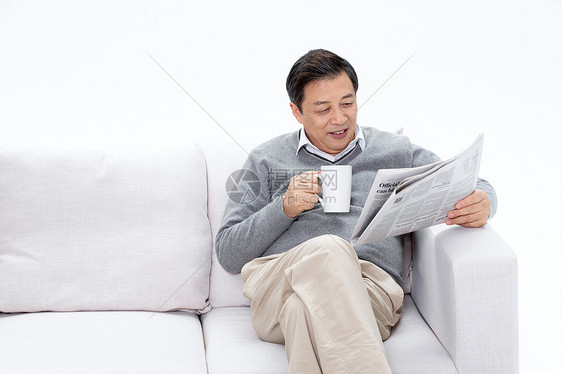 老人坐在沙发上拿着咖啡看报纸图片
