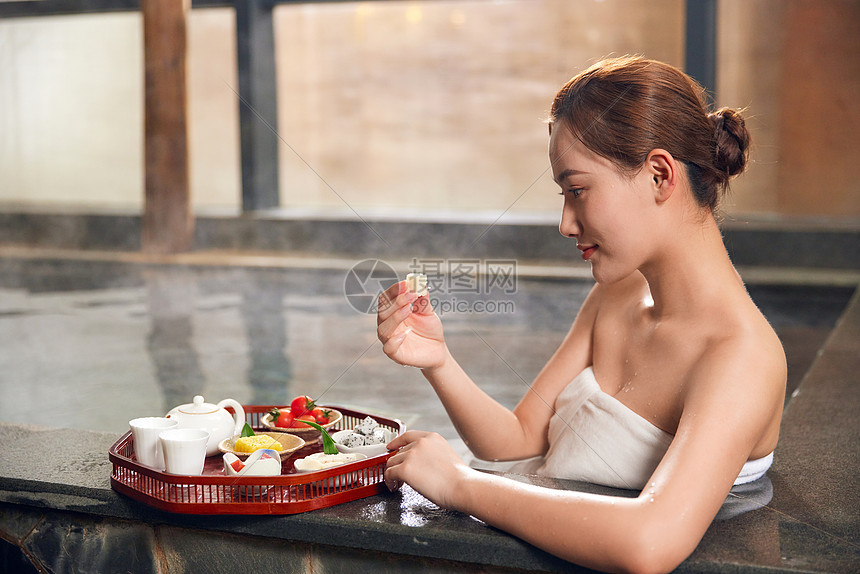 年轻女性泡温泉吃小食图片
