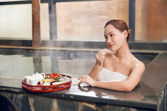 年轻女性泡温泉吃小食图片