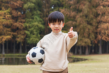 抱足球小男孩秋季小男孩公园里抱足球点赞背景