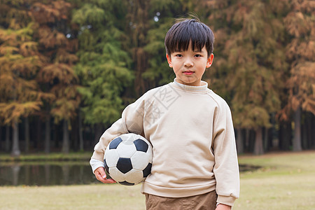 抱足球小男孩秋季小男孩公园里抱足球背景