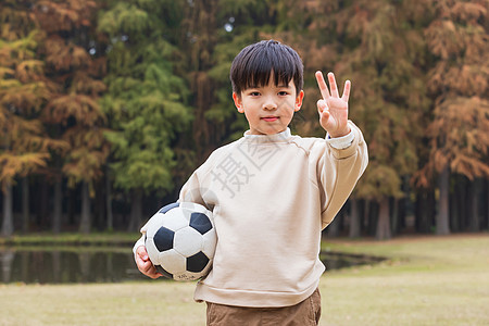 抱足球小男孩秋季小男孩公园里抱足球背景