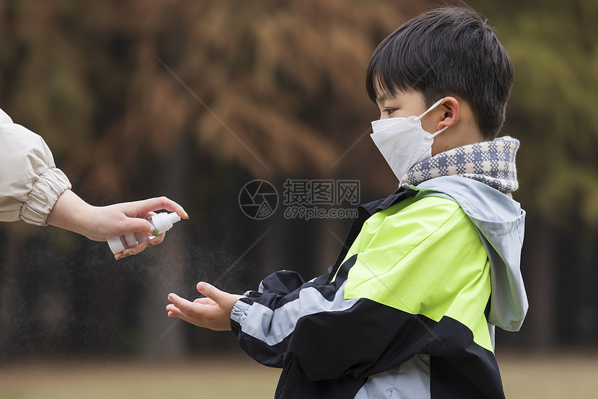 秋冬小男孩疫情期间逛公园手部消毒图片
