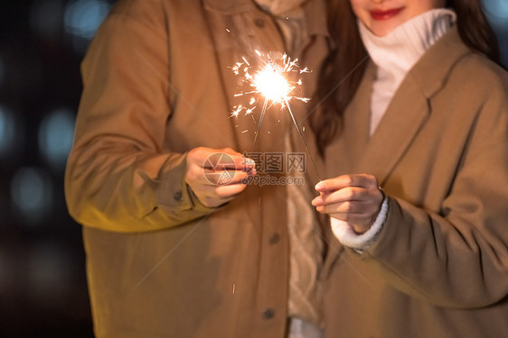 秋冬夜晚情侣室外放烟花特写图片