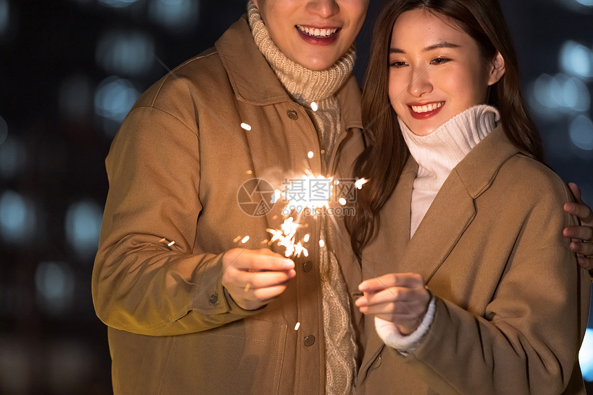 秋冬夜晚情侣室外放烟花特写图片