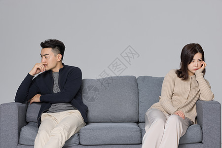 雨中的情侣吵架后的夫妻两人坐在沙发上背景