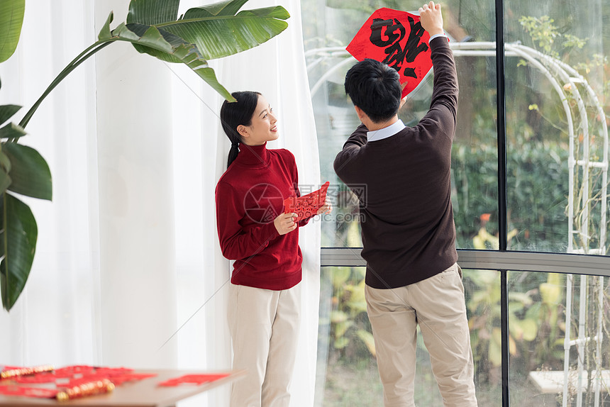 青年夫妻客厅贴春联迎新年图片