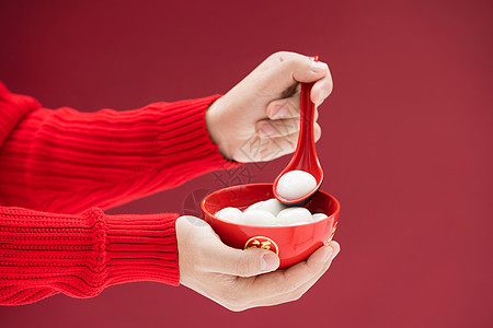 穿红色毛衣的手舀起一颗汤圆高清图片