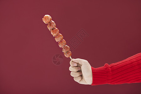 穿着红色毛衣的一只手拿着冰糖葫芦图片