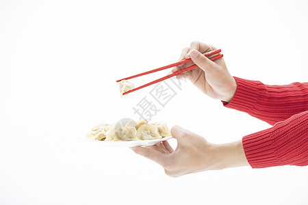 红色毛衣的手用筷子夹起饺子图片