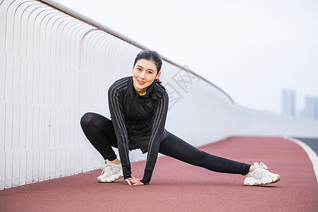 运动衣女性在跑道上做热身运动背景