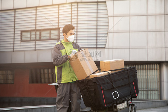 佩戴口罩的快递员户外整理快递图片